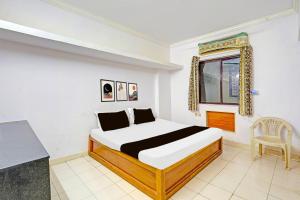 a bedroom with a bed and a window at Hotel O Sri Vasavi Nivas in Tirupati