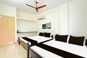 two beds in a room with a ceiling fan at Hotel O Sri Vasavi Nivas in Tirupati