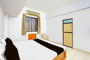 a bedroom with a bed and a window at Hotel O Sri Vasavi Nivas in Tirupati