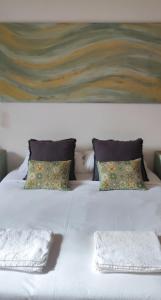 a white bed with two pillows and a painting at El Tercer Piso in Puente la Reina +9 photos