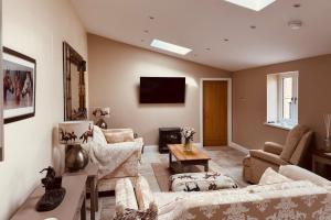 a living room with a couch and chairs and a tv at The Forge, Newly Converted Barn in Carnforth