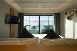 a bedroom with two beds and a view of a balcony at Andaman Cannacia Resort & Spa - SHA Extra Plus in Kata Beach +105 photos