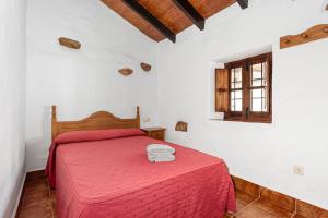 a bedroom with a red bed and a window at El Pajar in Málaga