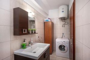 a bathroom with a sink and a washing machine at Sunset's Nest by Golden Host in Flogita
