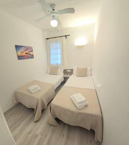 a room with two beds and a ceiling fan at Apartamento con terraza y vistas al mar en Son Bou in Son Bou +30 photos