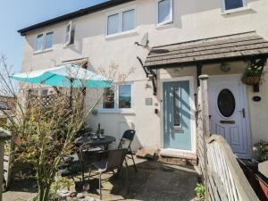 a house with a table and chairs and an umbrella at Malting Cottage in Dawlish