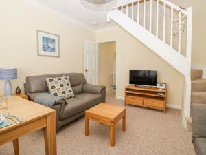 a living room with a couch and a tv at Malting Cottage in Dawlish