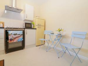 a kitchen with two chairs and a table and a tv at Malting Cottage in Dawlish +12 photos