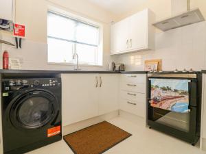 a kitchen with a washing machine and a tv at Malting Cottage in Dawlish