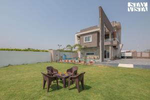a table and two chairs on the grass in front of a house at StayVista at Pinkal Farms with Pool, Lawn, Wi-Fi in Jaipur