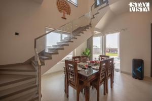 a dining room with a glass table and a staircase at StayVista at Pinkal Farms with Pool, Lawn, Wi-Fi in Jaipur