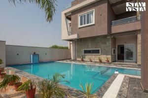 a swimming pool in front of a house at StayVista at Pinkal Farms with Pool, Lawn, Wi-Fi in Jaipur