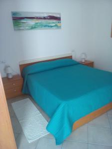 a bedroom with a bed with a blue comforter at Agriturismo Santa Barbara in Sarroch