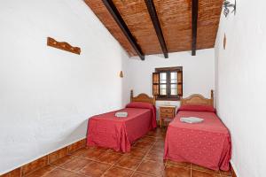 a room with two beds with red sheets in it at El Granero in Málaga