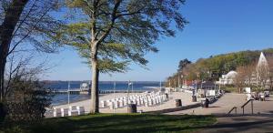 a row of white chairs on a sidewalk near the water at Schoen - Ferienwohnung Glücksand in Sandwig