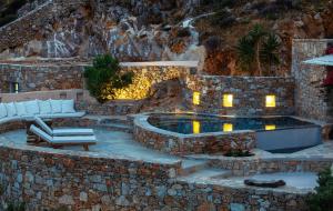an outdoor pool with a stone wall and a rock mountain at Villa Mikros Vorias in Karavostasi