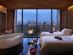 a hotel room with two beds and a bath tub at SO/ Bangkok in Bangkok