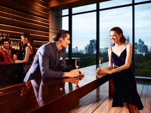 a man and woman standing at a bar with wine glasses at SO/ Bangkok in Bangkok