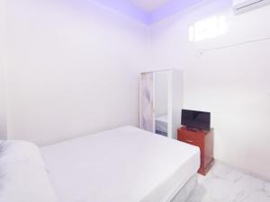 a white bedroom with a bed and a television at Ghe Ai Homestay RedPartner in Tulungagung