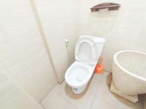 a bathroom with a toilet and a bath tub at Ghe Ai Homestay RedPartner in Tulungagung