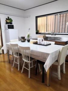 a kitchen with a large white table and chairs at Nippori Osaka Nishi-Tengachaya Guesthouse西天下茶屋アパートメント in Osaka