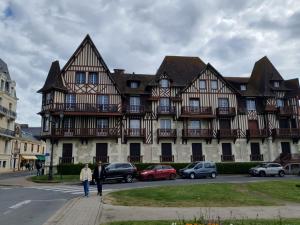a large building with cars parked in front of it at Mer et Style au coeur de l'éventail 3 pièces 2 chambres in Cabourg