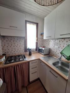 Una pequeña cocina con estufa y fregadero. en Bilocale per gli amanti dello sci, en Riolunato