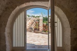 an open door with a view of a stone wall at HelloAPULIA Trulli Flora - Charming Trulli with Private Pool and Garden in Noci