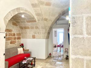 a living room with a red couch and a stone wall at Antica Pietra in Polignano a Mare