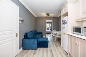a living room with a blue couch and a kitchen at Cosy 2-Bedroom Apartment near Airport in Dublin