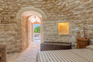 a bedroom with two beds and a stone wall at HelloAPULIA Trulli Flora - Charming Trulli with Private Pool and Garden in Noci