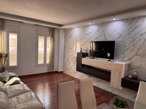 sala de estar con TV de pantalla plana en una pared de piedra en Selva House Sevilla, en Coria del Río