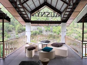 Una habitación con mesas y sillas en un balcón. en Ausnya Tirthan, en Banjār