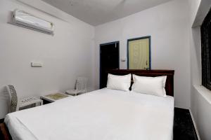 Un dormitorio con una cama blanca y una silla. en Hotel O HR, en Kundakal 45 fotos más