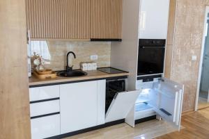 a kitchen with white cabinets and a sink at Apartman Sunce Lux A in Vrnjačka Banja