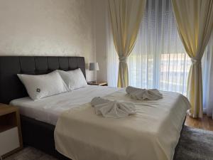 a bedroom with a bed with white sheets and curtains at Apartman Sunce Lux A in Vrnjačka Banja