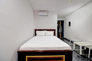 Un pequeño dormitorio con una cama y una silla. en Hotel O HR, en Kundakal