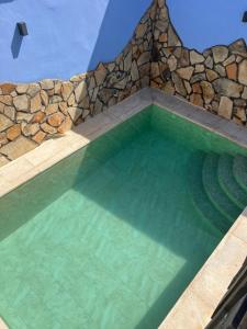 a large swimming pool with a stone wall and a pool at La Casa del Pueblo con piscina y barbacoa in Rincón de Ballesteros