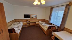 een kamer met twee bedden, een tafel en een tv bij Pokoje Gościnne Muszyna przy sądzie in Muszyna