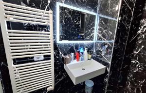 a black marble bathroom with a sink and a mirror at White Palace in Vlorë
