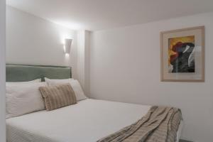 a bedroom with a white bed with a picture on the wall at Seannamon Apartment with sea view by 8essentially in Agios Nikolaos