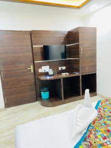 a bedroom with a desk and a bed with a television at Taj Comfort Inn in Agra