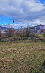 a field of grass with a house in the background at Casa de campo in Tolhuin