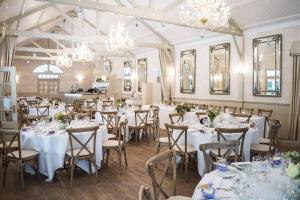 a banquet hall with white tables and chairs and chandeliers at Ravenwood Hall Hotel in Bury Saint Edmunds