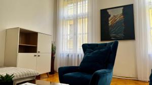 a living room with a blue chair and a cabinet at Spacious apartment in the city centre in Sarajevo