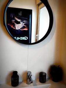 a mirror on a wall above a bathroom sink at Le cinoche in Woustviller