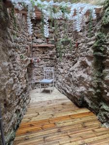 a chair sitting on a wooden floor next to a stone wall at Spacious village house completely renovated in Pennautier