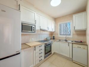 une cuisine avec des armoires blanches, un évier et un micro-ondes dans l'établissement Alta Mar Apartment, à Son Bou