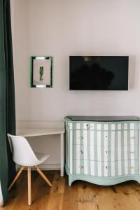 a dresser with a chair and a tv on a wall at La Bianca Dimora B&B in Gioia del Colle