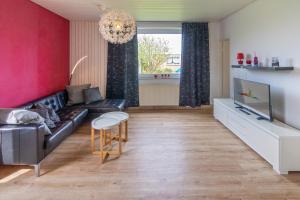 ein Wohnzimmer mit einem schwarzen Ledersofa und einem TV in der Unterkunft Ferienhaus Kim in Dornumersiel